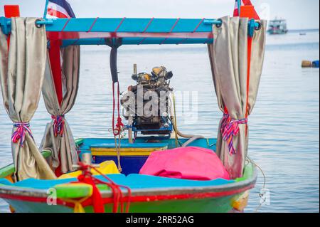 Le bateau thaïlandais aux couleurs vives avec un moteur très puissant pour le transport des touristes se trouve dans l'eau sous le ponton plein de touristes Banque D'Images