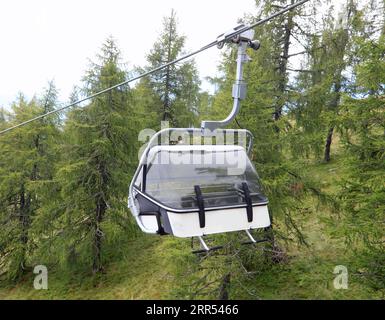 télésiège moderne pour le transport des randonneurs dans les hautes montagnes qui traverse la forêt en été Banque D'Images