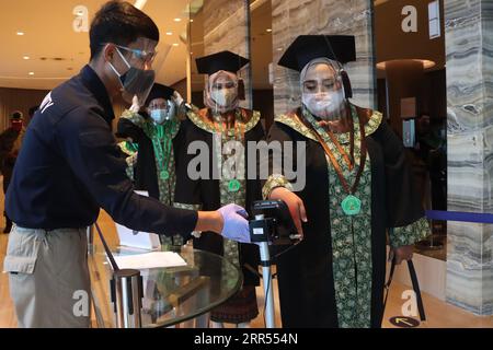 201223 -- PÉKIN, le 23 décembre 2020 -- les diplômés font la queue pour faire vérifier la température de leur corps lors de la cérémonie de remise des diplômes de l'Université islamique Sheikh Yusuf Tangerang Unis au milieu de l'épidémie de COVID-19 à Tangerang, en Indonésie. 22 décembre 2020. Photo de /Xinhua XINHUA PHOTOS DU JOUR DemyxSanjaya PUBLICATIONxNOTxINxCHN Banque D'Images