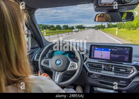 Vue d'une femme conduisant une BMW IX3 M Sport électrique. Banque D'Images