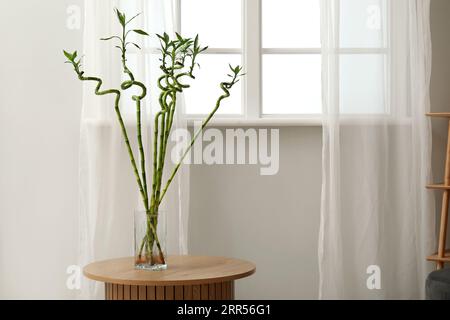 Vase avec tiges de bambou sur la table près de la fenêtre Banque D'Images