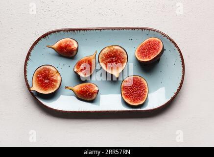 Assiette avec figues fraîches coupées sur fond gris Banque D'Images