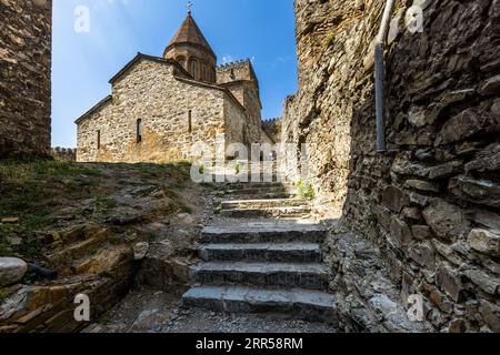 La forteresse d'Ananouri (géorgien ანანური) se dresse sur le réservoir de Zhinvali dans la municipalité de Dusheti, région de Mtskheta-Mtianeti, en Géorgie. Un escalier en pierre mène entre des murs en moellons à une église en dôme, peut-être l'église de l'Assomption (église de la Mère de Dieu) de 1689. Une tour crénelée s'élève derrière l'église. Les visiteurs se tiennent au sommet des escaliers. Un tuyau court le long du mur à droite. La forteresse était le siège des éristavis, les ducs d'Aragvi, qui régnaient sur la vallée depuis le XIIIe siècle. En 1739, les troupes du duc rival Shanshe de Ksani capturèrent la forteresse et l'incendièrent. Banque D'Images