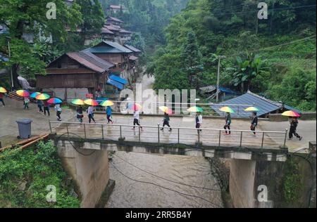 201231 -- RONGSHUI, 31 décembre 2020 -- une photo aérienne prise le 3 juin 2020 montre des femmes marchant sur un pont nouvellement construit en rentrant chez elles dans le village de Wuying, un village isolé habité par le groupe ethnique Miao à la frontière entre la région autonome du Guangxi Zhuang du sud de la Chine et la province du Guizhou du sud-ouest de la Chine. Situés dans une vallée profonde de cette région montagneuse, les habitants de Wuying ont souffert des terres arides de la région, de l environnement naturel inondé et des infrastructures de transport peu pratiques. Ces dernières années, les responsables locaux et les villageois se sont efforcés d améliorer la vie des gens par MAK Banque D'Images