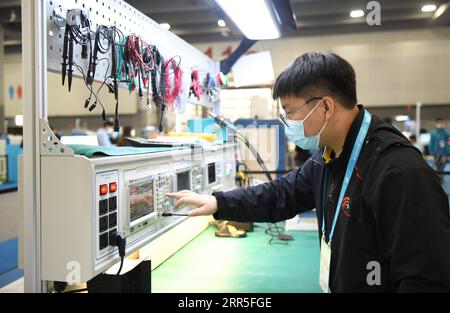 210105 -- CHONGQING, le 5 janvier 2021 -- Liang Pan travaille comme assistant de l'arbitre en électronique au premier concours national de compétences professionnelles à Guangzhou, dans la province du Guangdong, dans le sud de la Chine, le 10 décembre 2020. Liang Pan, qui a échoué à l'examen d'entrée au lycée, est maintenant professeur au Collège de technicien de transport ferroviaire de Chongqing. D'un élève de l'école secondaire professionnelle, un profane en électronique à un expert et un champion du monde, il a fallu 6 ans à Liang Pan pour réaliser le rêve. Les expériences de travail à un très jeune âge ont permis à Liang Pan de réaliser l'importance de la maîtrise Banque D'Images