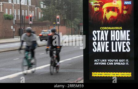 210110 -- LONDRES, le 10 janvier 2021 -- les gens passent devant un panneau publicitaire lisant Stay Home Save Lives à Londres, Grande-Bretagne, le 10 janvier 2020. Les décès liés au coronavirus en Grande-Bretagne ont dépassé 80 000 samedi avec 1 035 autres signalés dans le pays. BRETAGNE-LONDRES-COVID-19-CAS HanxYan PUBLICATIONxNOTxINxCHN Banque D'Images