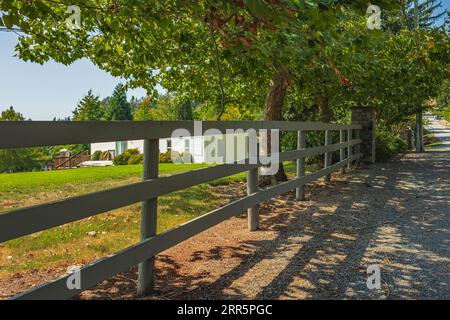 Long Split Rail Fence le long d'un champ herbeux menant à une grange ou une maison de ferme. Route de campagne le long des fermes agricoles. Clôture en bois le long du chemin Banque D'Images