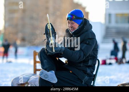210125 -- HULUNBUIR, le 25 janvier 2021 -- Wang Quanli décolle des patins à glace après avoir patiné sur une patinoire à Yakeshi de Hulun Buir, dans la région autonome de Mongolie intérieure du nord de la Chine, le 19 janvier 2021. Wang Quanli, 65 ans, qui a perdu ses jambes dans un accident il y a 35 ans, a commencé à patiner en 2019 et est rapidement devenu un passionné de ce sport. Après des années de pratique, il est maintenant un patineur qualifié avec des membres artificiels. SPCHINA-INNER MONGOLIA-HULUN BUIR-SKATINGCN LIANXZHEN PUBLICATIONXNOTXINXCHN Banque D'Images