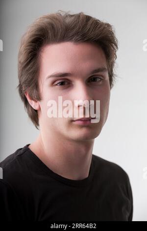 Sur une toile neutre, ce portrait d'homme séduisant brit. Sa chemise noire complète les cheveux bruns courts, mais c'est son look intense et son sourire tha Banque D'Images