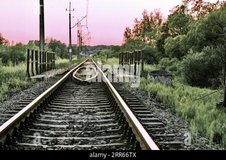 Voies ferrées et rails dans la campagne avec en toile de fond un beau coucher de soleil. Banque D'Images