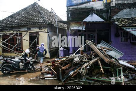210205 -- BEIJING, le 5 février 2021 -- Une femme tenant son enfant vérifie l'état de sa maison après que l'inondation eut frappé le sous-district de Gempol à Pasurauan, Java oriental, Indonésie, le 4 février 2021. En raison de la forte intensité des précipitations, le débordement de la rivière Kedunglarangan a endommagé des maisons dans la région. Photo de /Xinhua XINHUA PHOTOS DU JOUR Kurniawan PUBLICATIONxNOTxINxCHN Banque D'Images