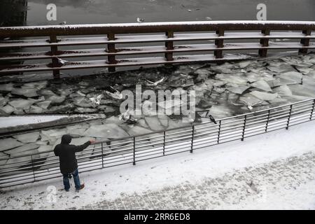 210210 -- BERLIN, le 10 février 2021 -- Un homme nourrit les oiseaux au bord de la rivière Spree à Berlin, capitale de l'Allemagne, le 9 février 2021. ALLEMAGNE-BERLIN-HIVER ShanxYuqi PUBLICATIONxNOTxINxCHN Banque D'Images