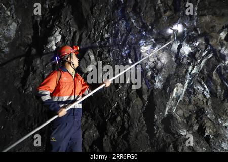 210212 -- JINCHANG, le 12 février 2021 -- Un mineur travaille sous terre dans la troisième zone minière du groupe Jinchuan à Jinchang, dans la province du Gansu du nord-ouest de la Chine, le 11 février 2021. Dans la mine sombre à plus de 600 mètres de profondeur, les machines minières rugissent et le minerai sur la bande transporteuse brille d'un lustre métallique. C'est la troisième zone minière du groupe Jinchuan à Jinchang, l'une des principales bases de production de nickel, cobalt et cuivre du pays. Les travailleurs ici qui ne sont pas rentrés chez eux pendant la fête du printemps se sont collés à leurs postes pour assurer l'exploitation minière de manière ordonnée. CHINA-GANSU Banque D'Images