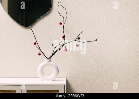 Intérieur minimaliste moderne avec décoration de Noël, vase tendance avec branches d'arbre décorées de petites boules Banque D'Images