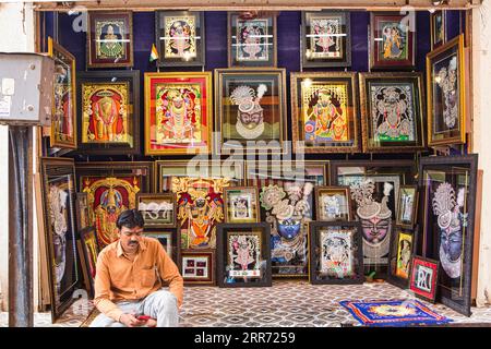 Vrindavan, Mathura, 19 octobre 2020 : un jeune commerçant regarde une idole mobile assise sur son atelier de photo et de peinture dans un marché de Vrindavan Banque D'Images