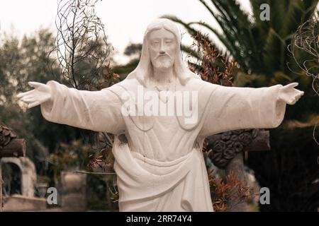 statue religieuse blanche figure du christ ouvrant ses bras dans un cimetière extérieur Banque D'Images