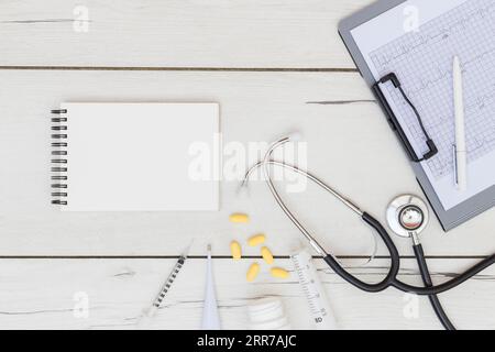 Bloc-notes en spirale vierge équipement médical s stéthoscope, presse-papiers ecg, bureau en bois Banque D'Images