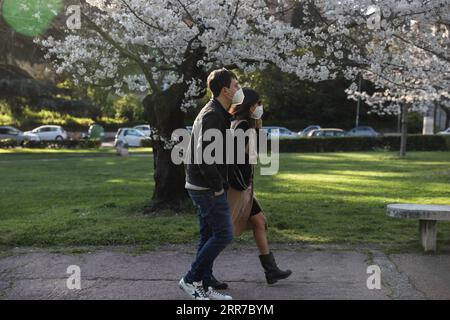 210325 -- ROME, le 25 mars 2021 -- des personnes portant un masque facial passent devant un cerisier à Rome, Italie, le 24 mars 2021. ITALIE-ROME-VIE QUOTIDIENNE-CERISIER EN FLEUR CHENGXTINGTING PUBLICATIONXNOTXINXCHN Banque D'Images