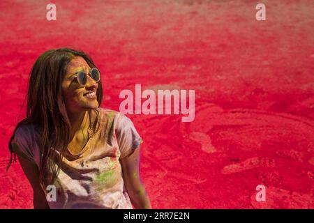 Portrait souriant jeune femme portant des lunettes de soleil salissant la couleur Holi Banque D'Images