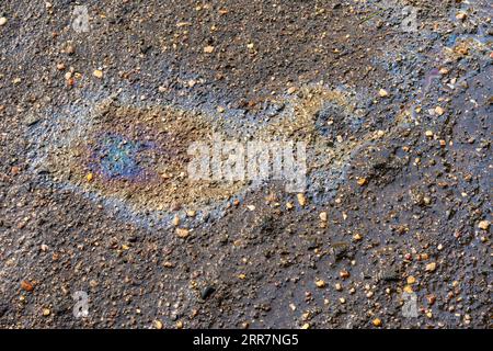 Fuite d'huile ou d'essence sous la voiture sur l'asphalte dans le stationnement. Banque D'Images