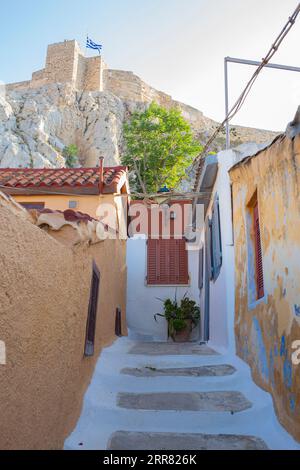Ancienne rue piétonne étroite à Plaka, Athènes avec une vue magnifique sur l'Acropole avec un drapeau grec agitant Banque D'Images