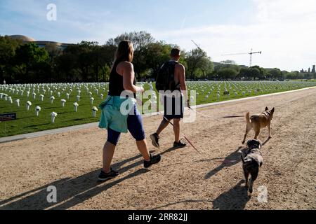 210414 -- WASHINGTON, le 14 avril 2021 -- les chiens marchant passent devant le National Mall où 40 000 fleurs de soie blanche sont installées pour honorer les près de 40 000 Américains qui meurent chaque année de violences par arme à feu à Washington, D.C., États-Unis, le 13 avril 2021. U.S.-WASHINGTON D.C.-GUN VIOLENCE-FLEURS EN SOIE LIUXJIE PUBLICATIONXNOTXINXCHN Banque D'Images