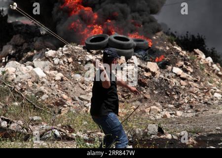 210416 -- NAPLOUSE, 16 avril 2021 -- Un manifestant palestinien utilise une fronde pour lancer des pierres sur des soldats israéliens lors d'affrontements après une manifestation contre l'expansion des colonies juives dans le village de Kufr Qadoom près de la ville de Naplouse, en Cisjordanie, le 16 avril 2021. Photo de /Xinhua MIDEAST-NAPLOUSE-CLASHS NidalxEshtayeh PUBLICATIONxNOTxINxCHN Banque D'Images