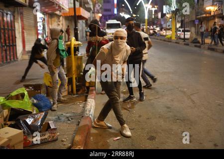 210425 -- HÉBRON, le 25 avril 2021 -- des manifestants palestiniens tiennent des pierres pour les jeter sur des soldats israéliens et des membres de la police des frontières israélienne lors d'une manifestation anti-israélienne dans la ville d'Hébron en Cisjordanie, le 24 avril 2021. Des affrontements ont éclaté dans les villes de Cisjordanie dans un contexte de tensions à la suite des affrontements à Jérusalem entre Palestiniens et Israéliens le 22 avril. Photo de /Xinhua MIDEAST-HEBRON-AFFRONTEMENTS MamounxWazwaz PUBLICATIONxNOTxINxCHN Banque D'Images