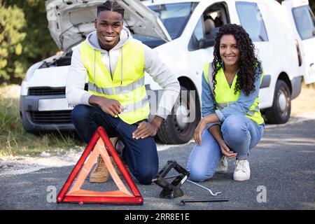 couple souriant et voiture en panne Banque D'Images