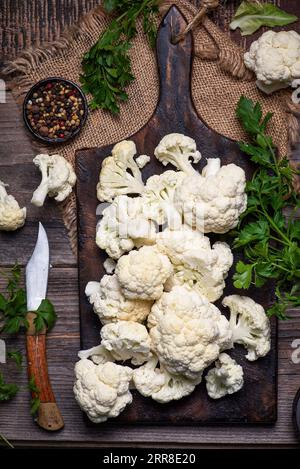 Chou-fleur frais et bio coupé en petits morceaux sur une planche à découper en bois et un fond en bois Banque D'Images