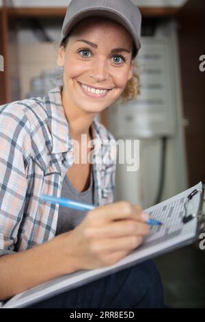 heureuse femme de livraison souriante en uniforme bleu avec presse-papiers Banque D'Images