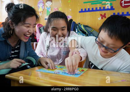 210515 -- NANJING, le 15 mai 2021 -- Zhou Wenqing joue avec des enfants dans une école d'éducation spéciale de Nanjing, dans la province du Jiangsu, dans l'est de la Chine, le 16 mai 2019. Zhou Wenqing, un étudiant aveugle de l'Université normale d'éducation spécialisée de Nanjing, a récemment reçu une offre provisoire de l'Université Renmin de Chine pour poursuivre une maîtrise en psychologie appliquée. Né en 1998, Zhou Wenqing a quitté sa ville natale à l'âge de huit ans pour poursuivre seul des études. En 2017, elle est admise à l'Université normale d'éducation spécialisée de Nanjing pour étudier la psychologie appliquée. Face aux défis que ou Banque D'Images