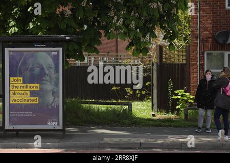 210520 -- BEDFORD, le 20 mai 2021 -- des gens attendent un autobus près d'un panneau publicitaire faisant la promotion du programme de vaccination du gouvernement britannique à Bedford, en Grande-Bretagne, le 19 mai 2021. Près de 3 000 cas de la variante du coronavirus détectés pour la première fois en Inde ont été signalés en Grande-Bretagne, a déclaré mercredi le secrétaire britannique à la Santé Matt Hancock. Des tests de pointe et des vaccinations seront déployés dans ces zones, notamment Bedford, Burnley, Hounslow, Kirklees, Leicester et North Tyneside, a déclaré Hancock. Photo de /Xinhua UK-BEDFORD-COVID-19-SURTENSION-VARIANT TimxIreland PUBLICATIONxNOTxINxCHN Banque D'Images