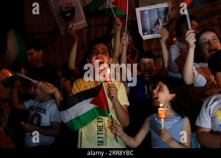 210520 -- NAPLOUSE, le 20 mai 2021 -- des enfants palestiniens brandissent des bougies et des drapeaux pour manifester leur solidarité avec les habitants de la bande de Gaza et protestent contre les frappes aériennes israéliennes en cours sur la bande de Gaza, dans la ville de Naplouse en Cisjordanie, le 20 mai 2021. Depuis le début de la campagne militaire israélienne le 10 mai, Israël pilonne Gaza avec des frappes aériennes et de l’artillerie qui détruisent des bâtiments résidentiels, des routes et d’autres infrastructures. Au moins 227 Palestiniens ont été tués, dont 64 enfants et 38 femmes, selon les responsables palestiniens de la santé dans la bande de Gaza. En Israël, 12 personnes h Banque D'Images