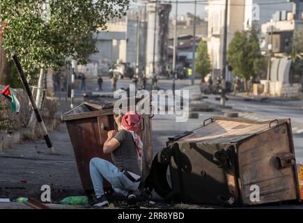 210520 -- BETHLÉEM, le 20 mai 2021 -- Un manifestant palestinien utilise une fronde pour lancer une pierre sur des membres de la sécurité israélienne lors d'une manifestation contre les frappes aériennes israéliennes continues sur la bande de Gaza, dans la ville de Bethléem en Cisjordanie, le 20 mai 2021. Depuis le début de la campagne militaire israélienne le 10 mai, Israël pilonne Gaza avec des frappes aériennes et de l’artillerie qui détruisent des bâtiments résidentiels, des routes et d’autres infrastructures. Au moins 227 Palestiniens ont été tués, dont 64 enfants et 38 femmes, selon les responsables palestiniens de la santé dans la bande de Gaza. En Israël, 12 personnes ha Banque D'Images