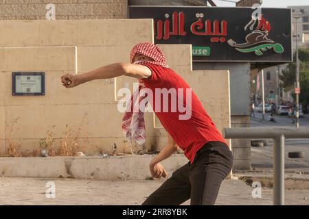 210520 -- BETHLÉEM, le 20 mai 2021 -- Un manifestant palestinien jette une pierre sur des membres de la sécurité israélienne lors d'une manifestation contre la poursuite des frappes aériennes israéliennes sur la bande de Gaza, dans la ville de Bethléem en Cisjordanie, le 20 mai 2021. Depuis le début de la campagne militaire israélienne le 10 mai, Israël pilonne Gaza avec des frappes aériennes et de l’artillerie qui détruisent des bâtiments résidentiels, des routes et d’autres infrastructures. Au moins 227 Palestiniens ont été tués, dont 64 enfants et 38 femmes, selon les responsables palestiniens de la santé dans la bande de Gaza. En Israël, 12 personnes ont été tuées, inc Banque D'Images