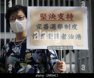 210527 -- HONG KONG, le 27 mai 2021 -- Une femme tient une affiche en faveur du projet de loi de 2021 sur l'amélioration du système électoral consolidé devant le Conseil législatif à Hong Kong, dans le sud de la Chine, le 27 mai 2021. La législature de Hong Kong a adopté jeudi des amendements aux lois électorales, clôturant la législation locale visant à améliorer le système électoral du centre financier. Le projet de loi de 2021 sur l amélioration du système électoral consolidé a été approuvé en troisième lecture par le LegCo du Conseil législatif de la région administrative spéciale de Hong Kong de la République populaire de Chine, après avoir été porté devant le lawmak Banque D'Images