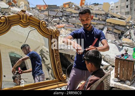 210602 -- PÉKIN, le 2 juin 2021 -- Abdullah al-Zawara a, 23 ans, un barbier palestinien, travaille gratuitement pour un client près de sa maison, détruite lors de frappes aériennes israéliennes dans la ville de Beit Lahia, dans le nord de la bande de Gaza, le 26 mai 2021. Photo par /Xinhua Portraits de mai 2021 RizekxAbdeljawad PUBLICATIONxNOTxINxCHN Banque D'Images