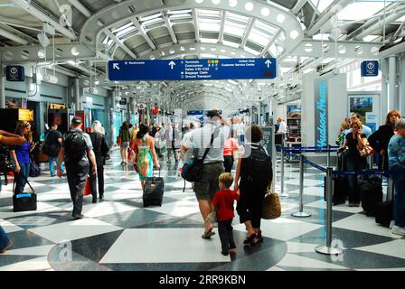 Une famille voyageant se précipite dans le terminal pour prendre leur vol alors qu'ils se promènent autour des autres voyageurs à l'aéroport international O'Hare de Chicago Banque D'Images