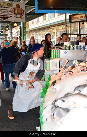 Un travailleur du marché se prépare à jeter un poisson congelé pour l'emballage dans le lancer du poisson, au marché de Pike place, Seattle Banque D'Images