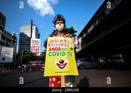 210712 -- JAKARTA, le 12 juillet 2021 -- Un membre d'Aku Badut Indonesia, une communauté de clowns, présente une pancarte lors d'une campagne de sensibilisation au port du masque facial pendant l'épidémie de COVID-19 dans une rue de Jakarta, Indonésie, le 12 juillet 2021. L’Indonésie a enregistré lundi 40 427 cas nouvellement confirmés de COVID-19 au cours des dernières 24 heures, marquant le pic quotidien le plus élevé et portant le total à 2 567 630, a déclaré le ministère de la Santé. INDONÉSIE-JAKARTA-COVID-19-CAMPAGNE DE SENSIBILISATION AU MASQUE FACIAL AGUNGXKUNCAHYAXB. PUBLICATIONxNOTxINxCHN Banque D'Images