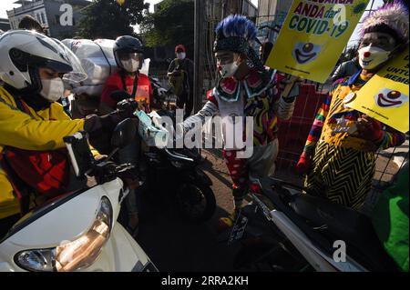 210712 -- JAKARTA, le 12 juillet 2021 -- des membres d'Aku Badut Indonesia, une communauté de clowns, distribuent des masques faciaux gratuits aux coureurs lors d'une campagne de sensibilisation au port de masques faciaux pendant l'épidémie de COVID-19 dans une rue de Jakarta, Indonésie, le 12 juillet 2021. L’Indonésie a enregistré lundi 40 427 cas nouvellement confirmés de COVID-19 au cours des dernières 24 heures, marquant le pic quotidien le plus élevé et portant le total à 2 567 630, a déclaré le ministère de la Santé. INDONÉSIE-JAKARTA-COVID-19-CAMPAGNE DE SENSIBILISATION AU MASQUE FACIAL AGUNGXKUNCAHYAXB. PUBLICATIONxNOTxINxCHN Banque D'Images