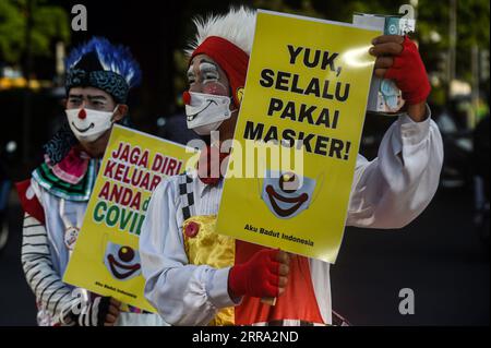 210712 -- JAKARTA, le 12 juillet 2021 -- un membre d'Aku Badut Indonesia, une communauté de clowns, présente des pancartes lors d'une campagne de sensibilisation au port du masque facial pendant l'épidémie de COVID-19 dans une rue de Jakarta, Indonésie, le 12 juillet 2021. L’Indonésie a enregistré lundi 40 427 cas nouvellement confirmés de COVID-19 au cours des dernières 24 heures, marquant le pic quotidien le plus élevé et portant le total à 2 567 630, a déclaré le ministère de la Santé. INDONÉSIE-JAKARTA-COVID-19-CAMPAGNE DE SENSIBILISATION AU MASQUE FACIAL AGUNGXKUNCAHYAXB. PUBLICATIONxNOTxINxCHN Banque D'Images