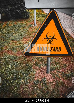 Signe de danger biologique de contamination biologique de forme triangulaire de danger, sur sol contaminé par l'herbe. Banque D'Images