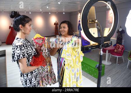 210720 -- URUMQI, le 20 juillet 2021 -- Une directrice R d'une entreprise de vêtements, qui reçoit un soutien financier de la province du Guangdong du sud de la Chine, discute avec son employée des détails de la diffusion en direct pour promouvoir les ventes dans le comté de Payzawat, dans la région autonome ouïgour du Xinjiang, au nord-ouest de la Chine, le 11 juillet 2021. Xinhua Headlines : la Chine met en commun des ressources pour aider le Xinjiang à atteindre une prospérité modérée DingxLei PUBLICATIONxNOTxINxCHN Banque D'Images