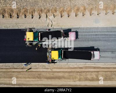 210720 -- FUHAI, le 20 juillet 2021 -- sur cette photo aérienne, des véhicules pavent une section d'une autoroute transdésertique avec de l'asphalte dans la région autonome ouïgoure du Xinjiang du nord-ouest de la Chine, le 16 juillet 2021. La construction de la première voie express transdésertique au Xinjiang s'est déroulée sans heurts. La voie express, qui relie la préfecture d'Altay et la capitale régionale d'Urumqi, s'étend sur quelque 343 km, avec des sections de plus de 150 km construites à travers le désert. CHINE-XINJIANG-CROSS-DESERT EXPRESSWAY CONSTRUCTION CN GAOXHAN PUBLICATIONXNOTXINXCHN Banque D'Images