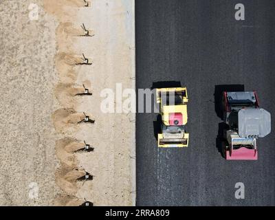 210720 -- FUHAI, le 20 juillet 2021 -- sur cette photo aérienne, des véhicules pavent une section d'une autoroute transdésertique avec de l'asphalte dans la région autonome ouïgoure du Xinjiang du nord-ouest de la Chine, le 16 juillet 2021. La construction de la première voie express transdésertique au Xinjiang s'est déroulée sans heurts. La voie express, qui relie la préfecture d'Altay et la capitale régionale d'Urumqi, s'étend sur quelque 343 km, avec des sections de plus de 150 km construites à travers le désert. CHINE-XINJIANG-CROSS-DESERT EXPRESSWAY CONSTRUCTION CN GAOXHAN PUBLICATIONXNOTXINXCHN Banque D'Images