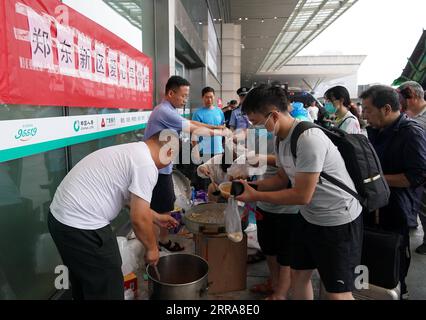 Chine, Überschwemmungen durch Starkregen à Zhengzhou 210721 -- ZHENGZHOU, le 21 juillet 2021 -- des employés distribuent un petit déjeuner aux passagers bloqués à la gare ferroviaire de Zhengzhou est à Zhengzhou, capitale de la province du Henan, le 21 juillet 2021. Zhengzhou a été frappé par des pluies torrentielles record. Plus de 160 trains ont arrêté leurs services à la gare de Zhengzhou East Railway Station, transportant un grand nombre de passagers. Des bus ont été dépêchés pour transférer les passagers bloqués vers la zone de sécurité dans le district urbain et le nombre de personnes piégées ici a considérablement diminué mercredi matin. Banque D'Images
