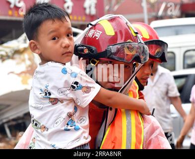 Chine, Überschwemmungen durch Starkregen in Zhengzhou 210721 -- ZHENGZHOU, le 21 juillet 2021 -- Un garçon est transféré dans un lieu sûr dans la ville de Mihe, dans la ville de Gongyi, province du Henan, au centre de la Chine, le 21 juillet 2021. La ville de Mihe a subi de gros dégâts en raison des fortes pluies du 20 juillet, avec un grand nombre de routes endommagées et des véhicules inondés. CHINA-HENAN-FLOOD-RESCUE CN LixJianan PUBLICATIONxNOTxINxCHN Banque D'Images