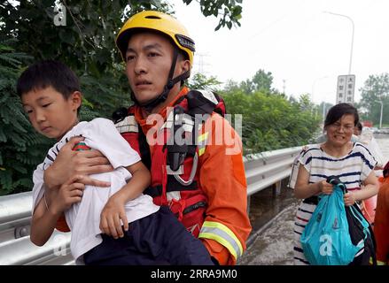 Chine, Überschwemmungen durch Starkregen à Zhengzhou 210723 -- ZHENGZHOU, 23 juillet 2021 -- Un sauveteur aide à évacuer un enfant à l'entrée d'une autoroute à Zhengzhou, province du Henan, touchée par les inondations, le 23 juillet 2021. CHINA-HENAN-ZHENGZHOU-RAINBOW-EVACUATION CN LIXAN PUBLICATIONXNOTXINXCHN Banque D'Images